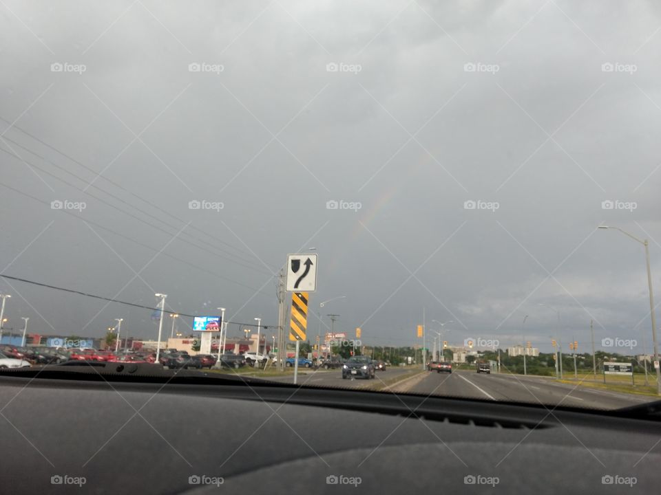 A rainbow over suburbia on a cloudy day.