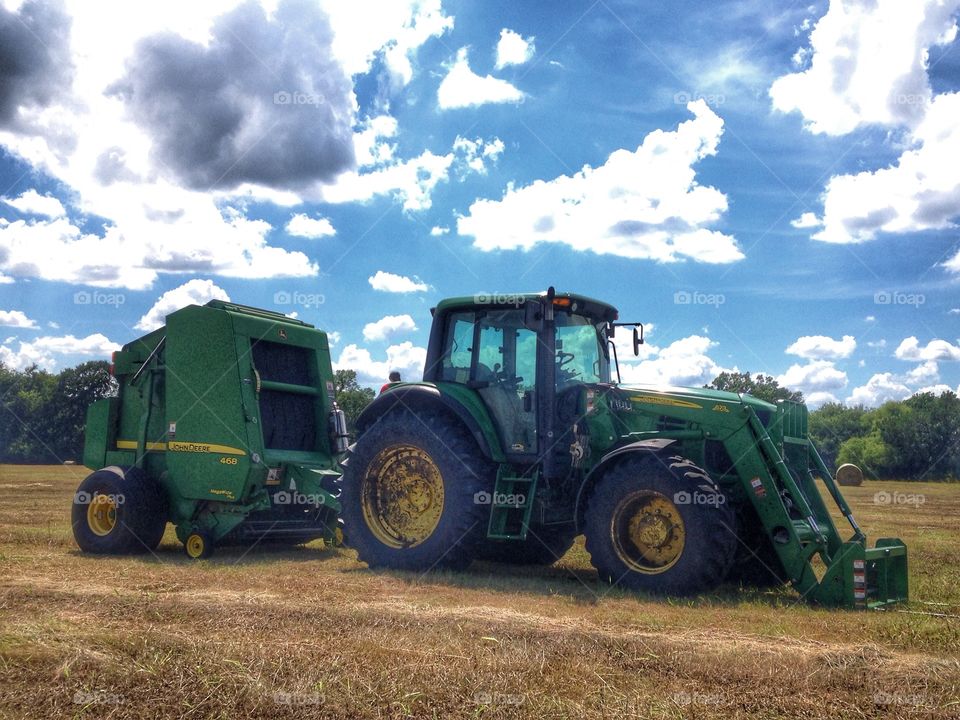 A day at the farm. Tractor and bailer in a field