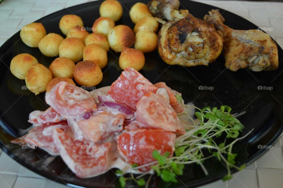 A delicious dish. Chicken legs with baked potato balls and salad with fresh tomatoes ,cress and onion.