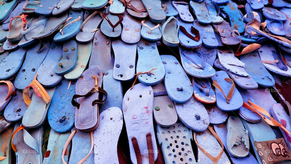 Portrait of piles of colorful flip-flops that are neatly arranged and look aesthetically pleasing, dominated by blue sandals.
