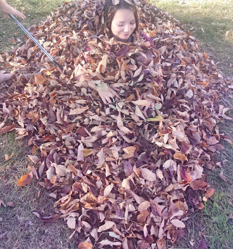 Teenage girl buried in dry autumn leaves