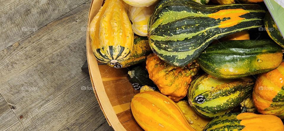 variety of yellow orange green gourds in a wooden basket for sale in an Oregon store