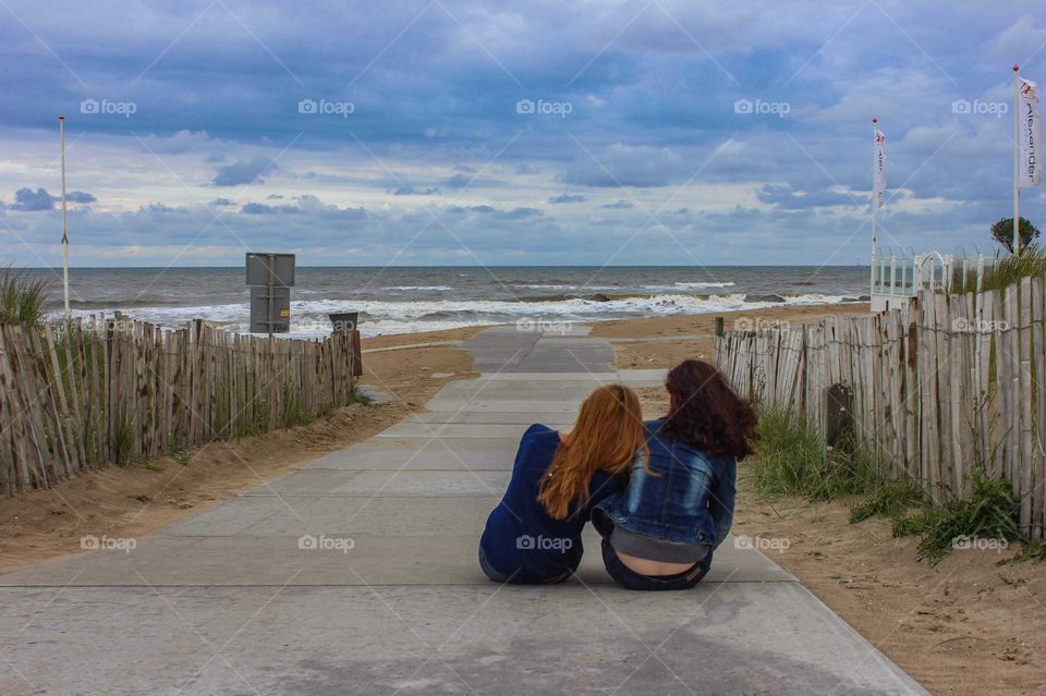 Girls sitting on the coast of the North Sea.