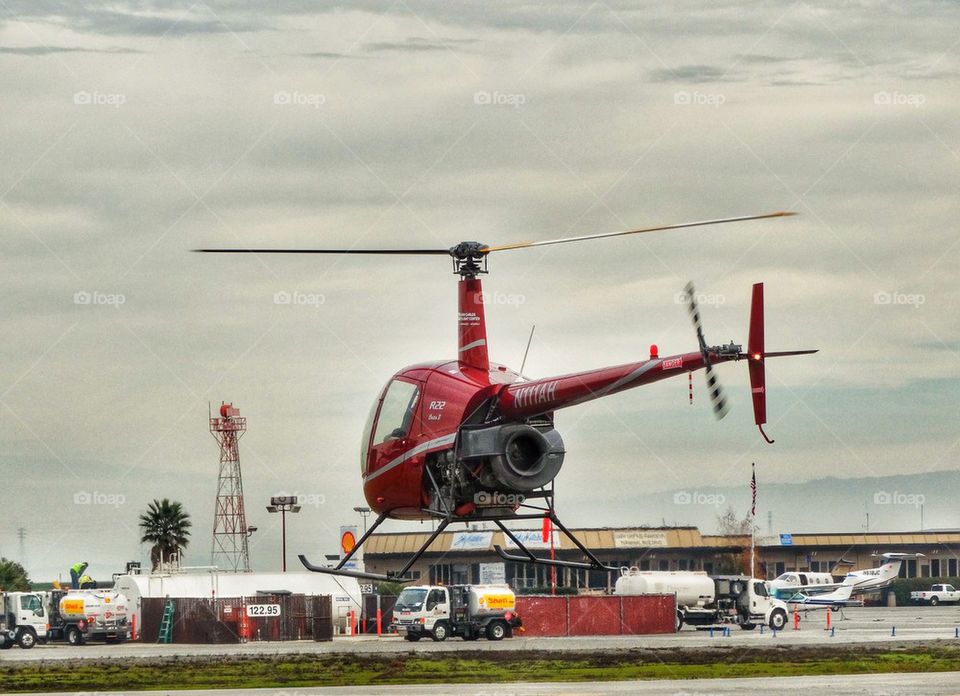 Helicopter Hovering Over Airfield. Robinson R-22 Helicopter Preparing For Takeoff