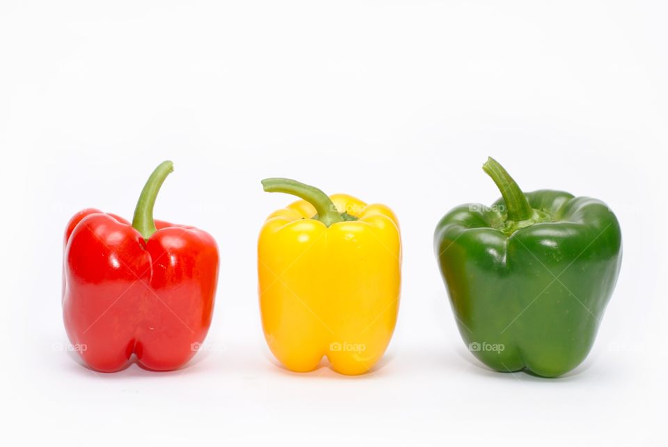 Three colorful peppers, red, yellow, green on a white background