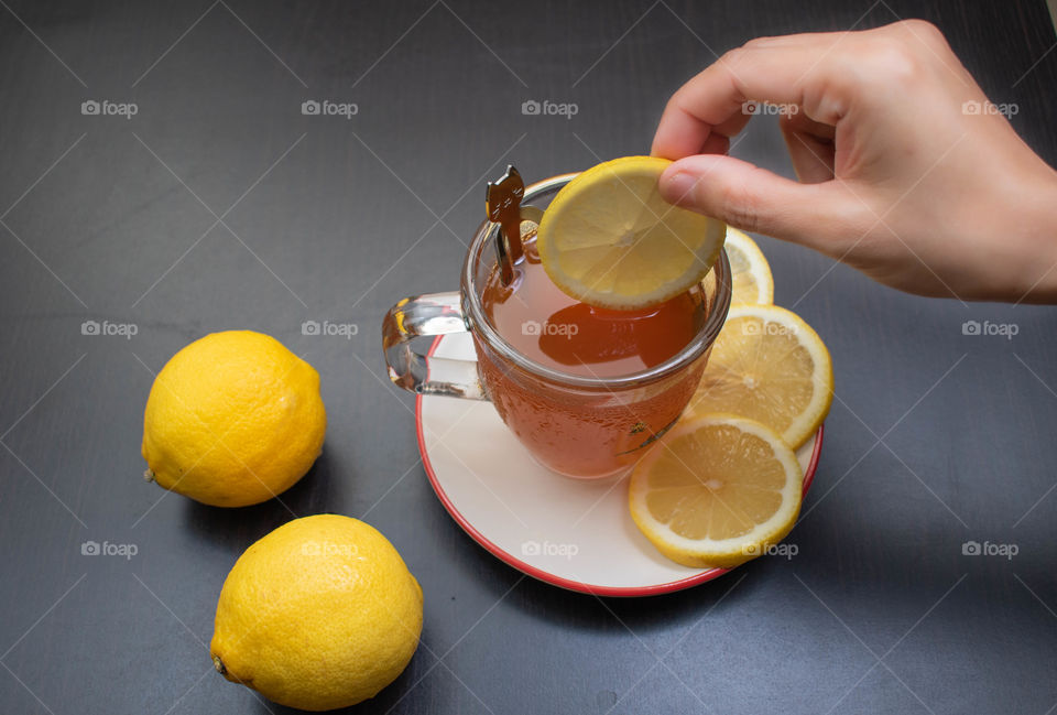 Adding slice of lemon into lemon tea