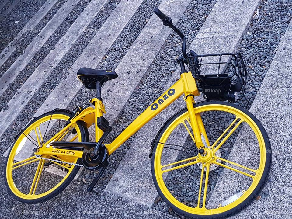 A yellow bike is left on a zebra crossing. No owner to be found but still the bike waits.