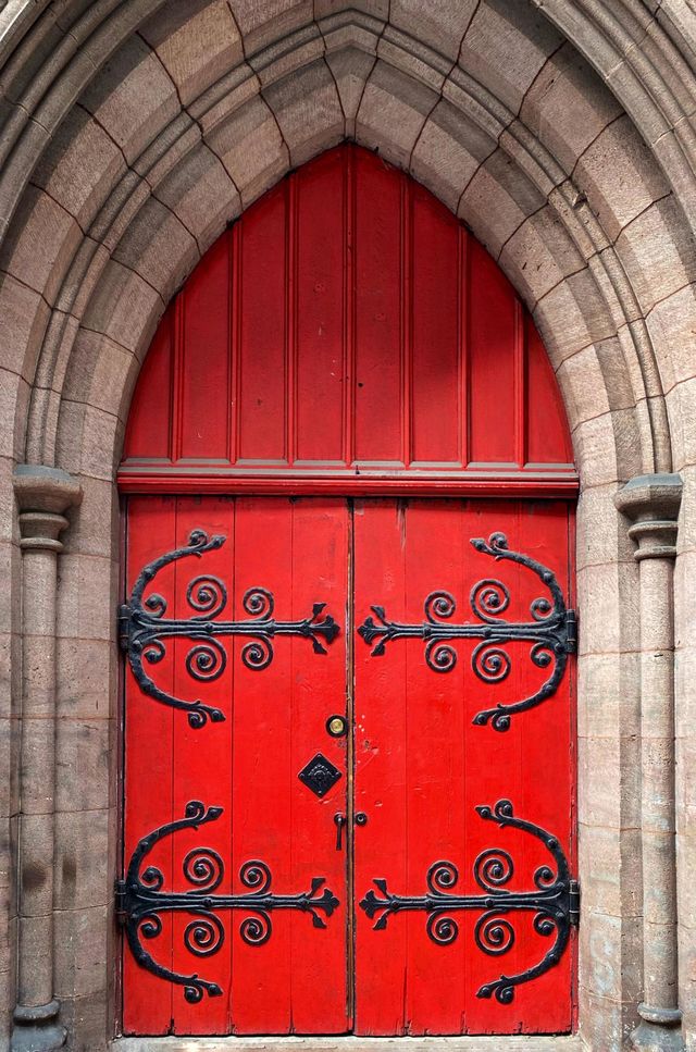 Red church door with elaborate iron hinges