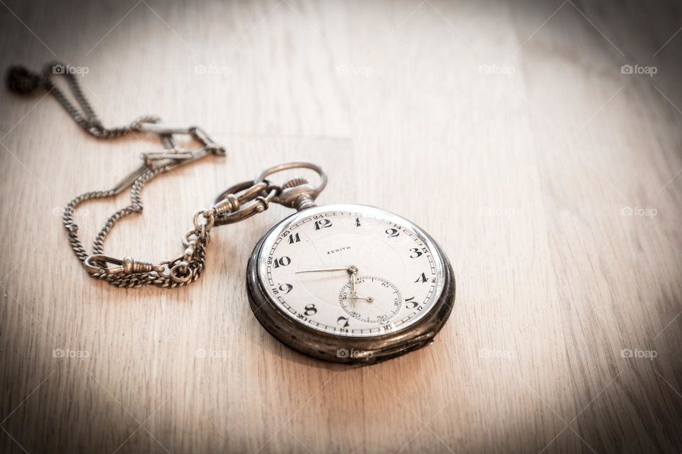 Closeup of one old pocket clock in vintage mood on wooden table with dark vignette 