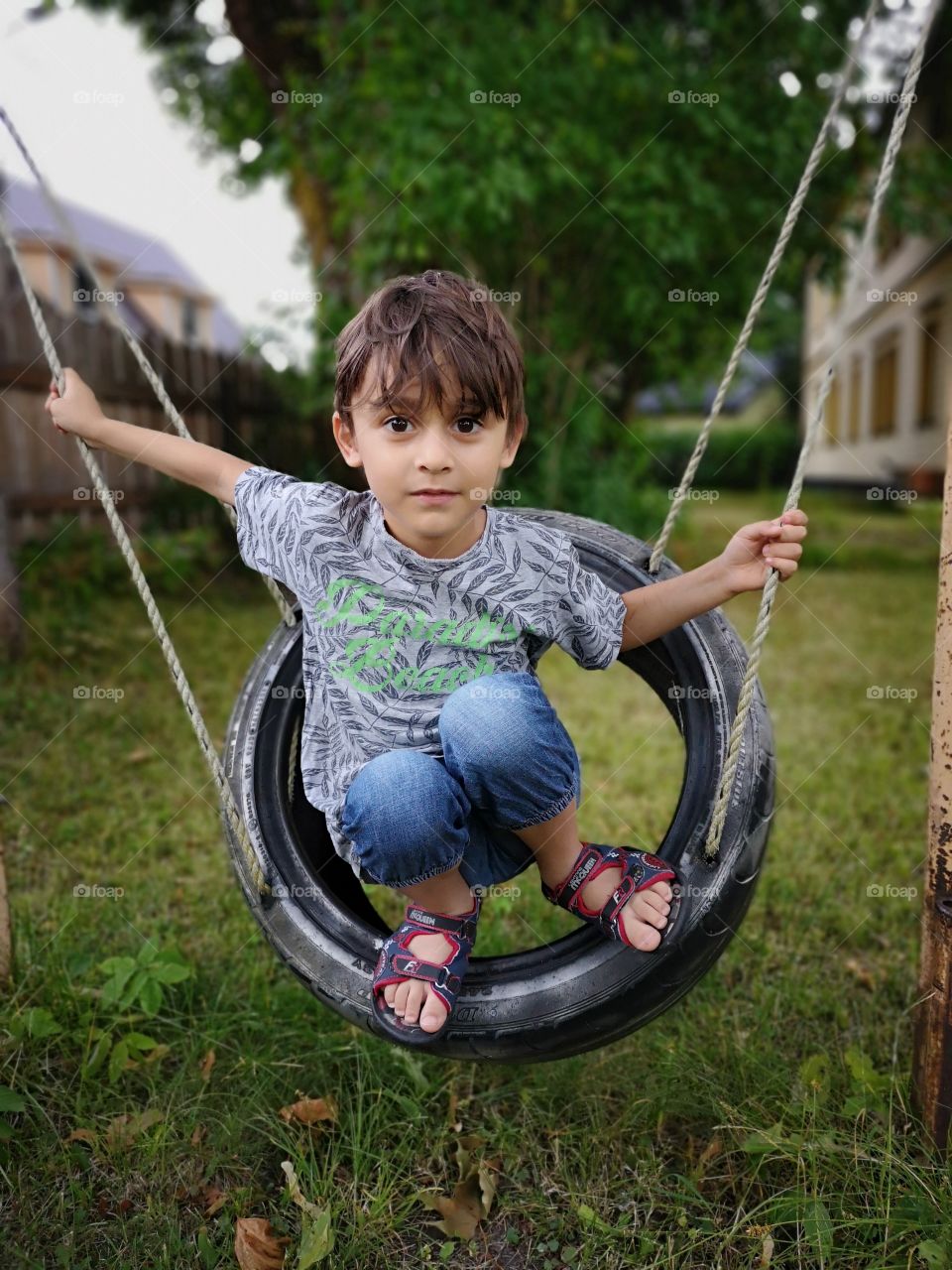 Cute boy on swing made of recycled car tire