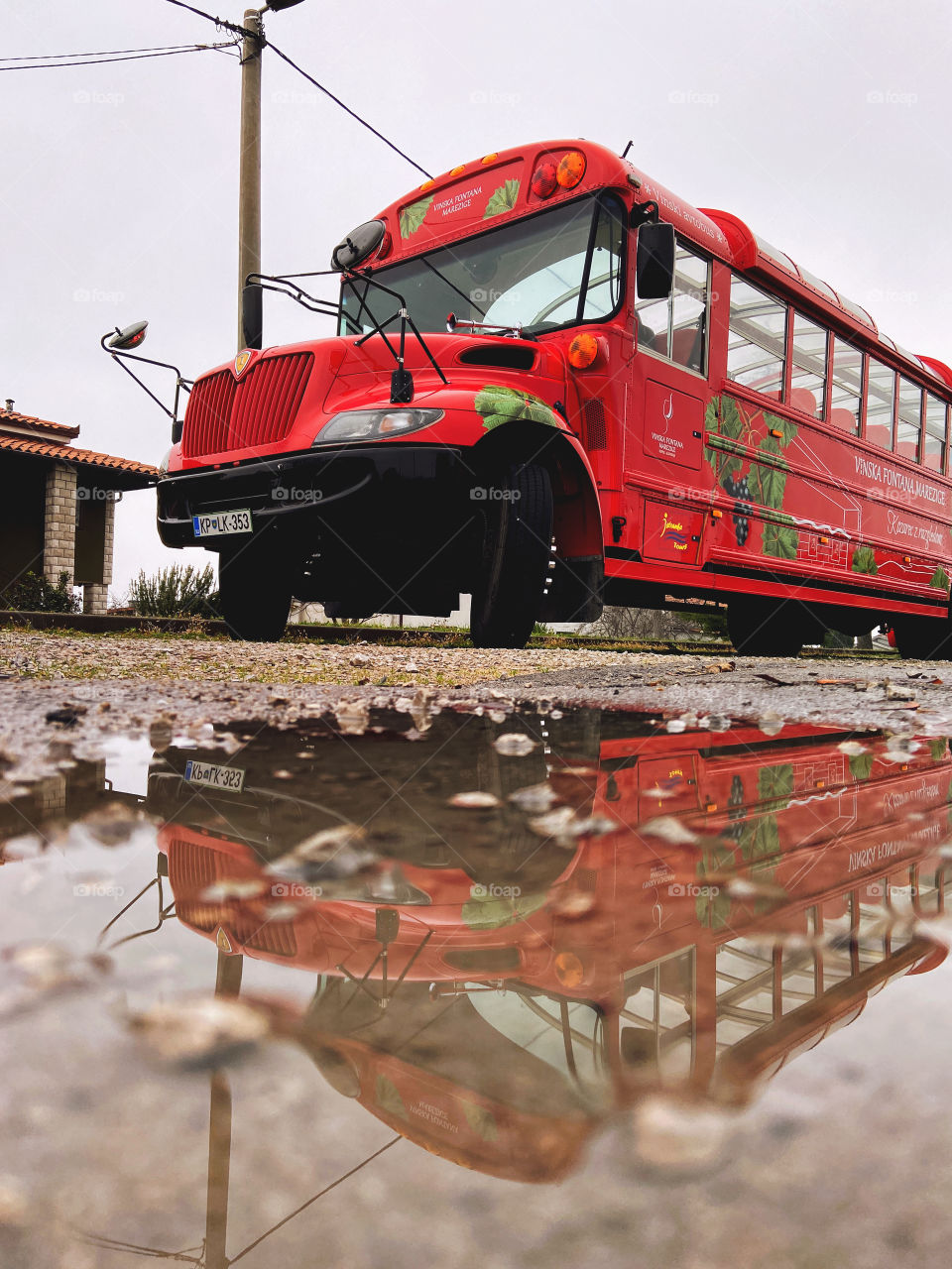 Image of a large red tourist bus reflected in a puddle in winter. Travel conception. Slovenia.