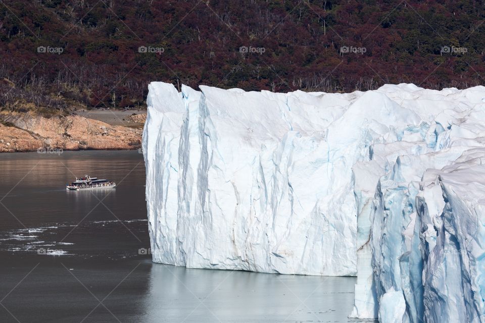 Los Glaciares National Park. Photo of Argentinian glacier with small boat next to glacier. Mountains in the background.