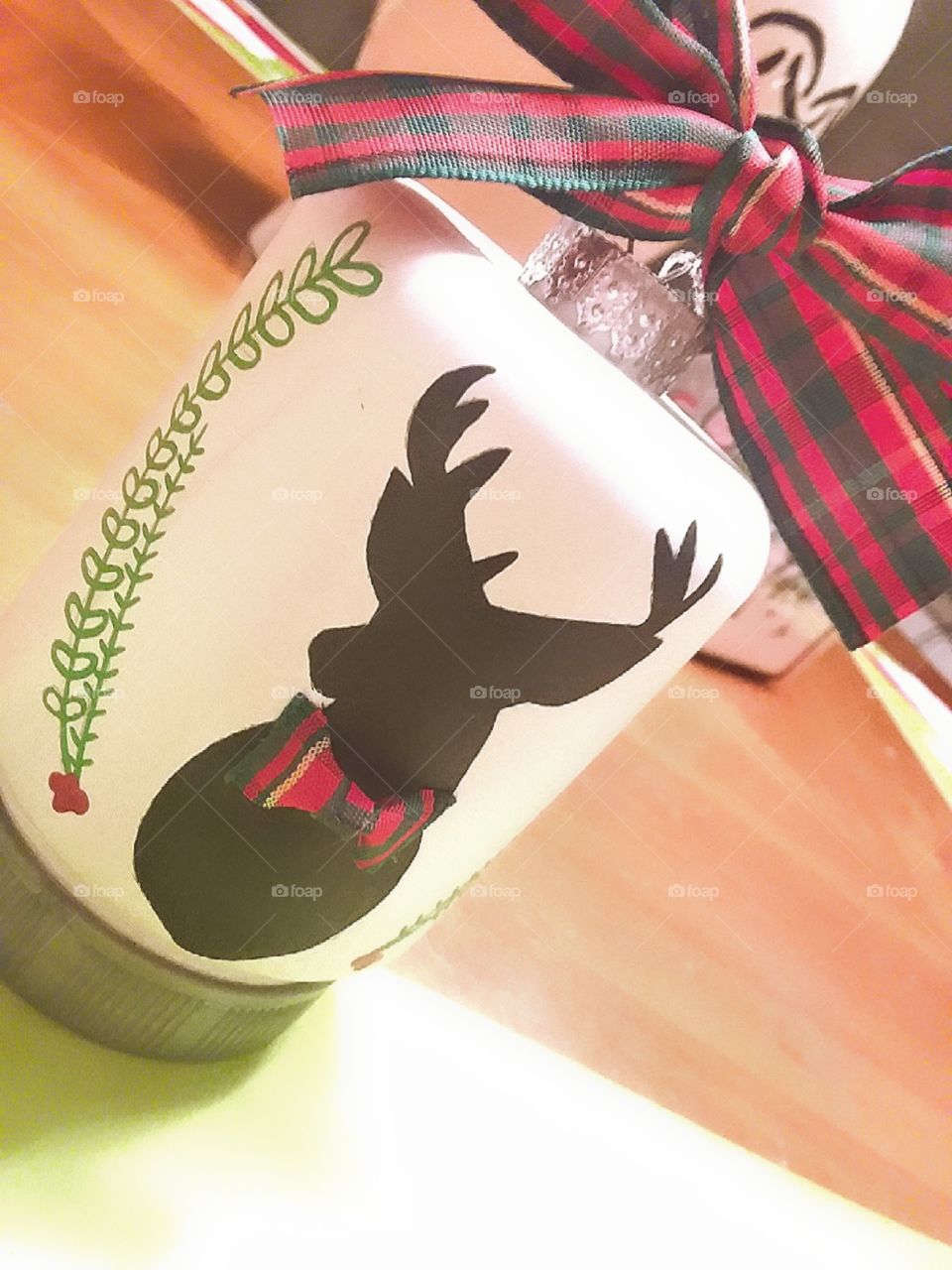 An adorable handpainted Christmas ornament silhouette of a deer framed by a half wreath