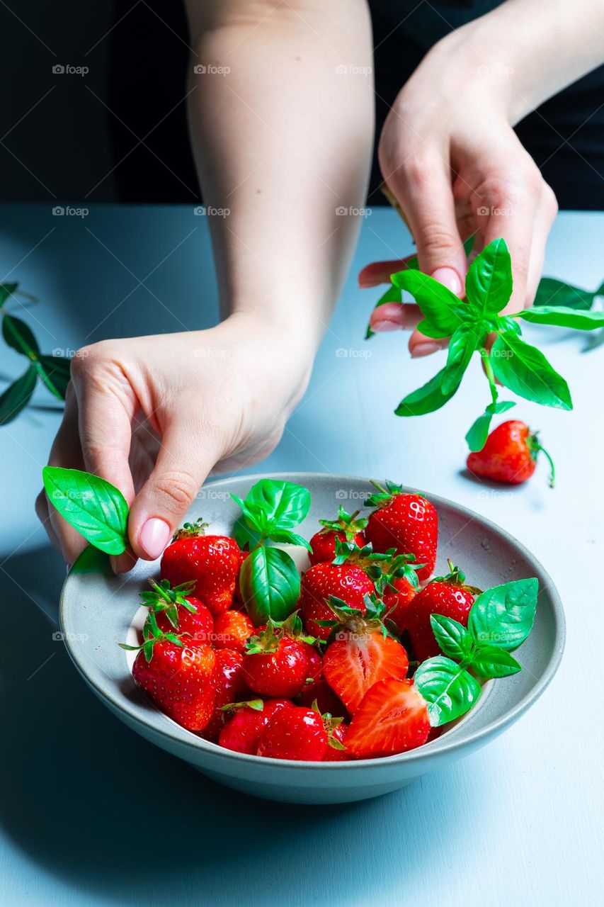 the girl prepares a fresh fruit salad from ripe garden strawberries - healthy food, berries and fruits, bright vitamins. Promotion of a healthy lifestyle