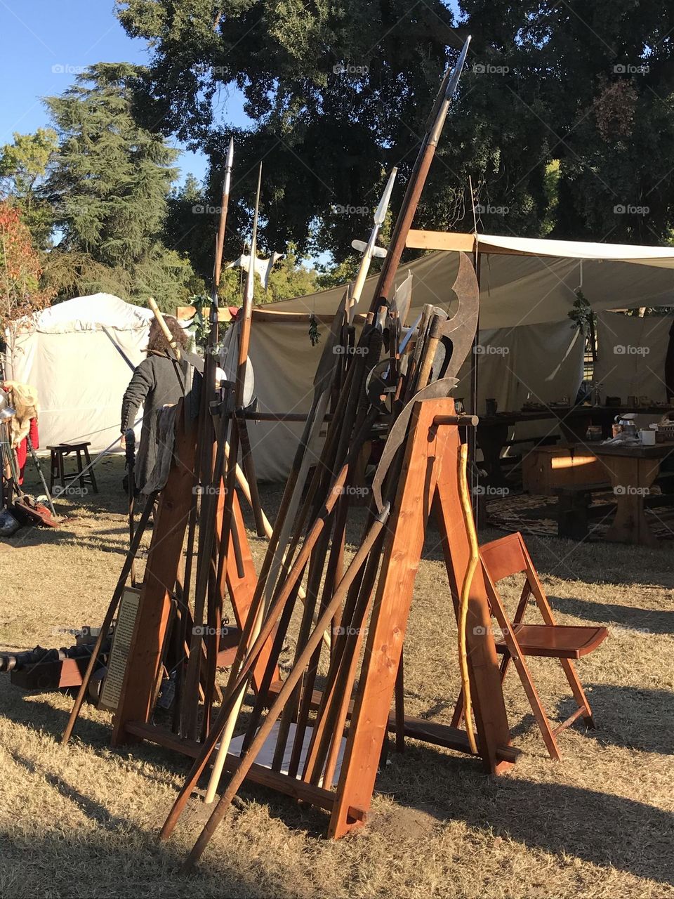 An impressive array of battlefield bladed weapons on display. This assortment of fighting implements are ready to be employed conveniently as they sit on the rack in the encampment of an Irish guild during the Renaissance Faire.