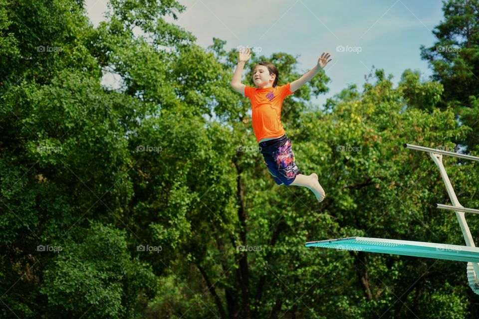 Young Boy Leaping Off A Diving Board