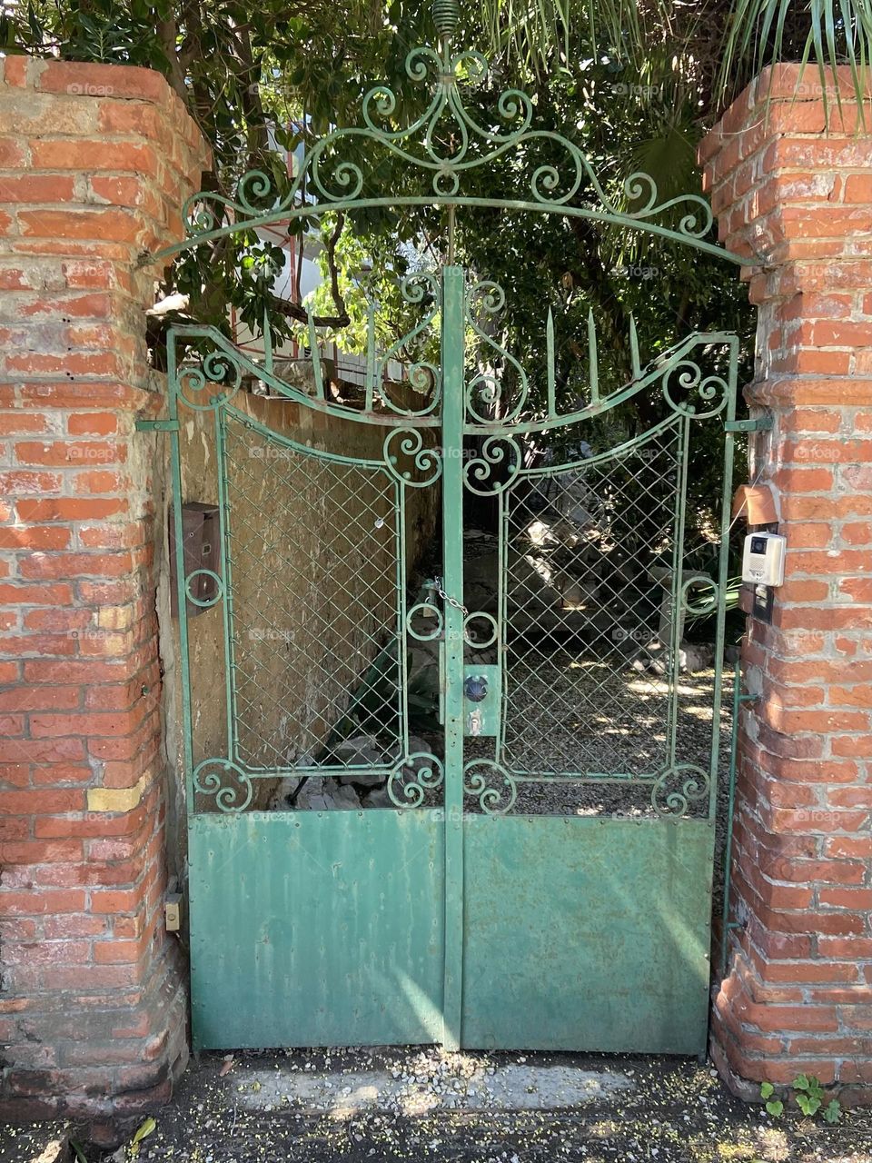 A red brick fence with a green gate.