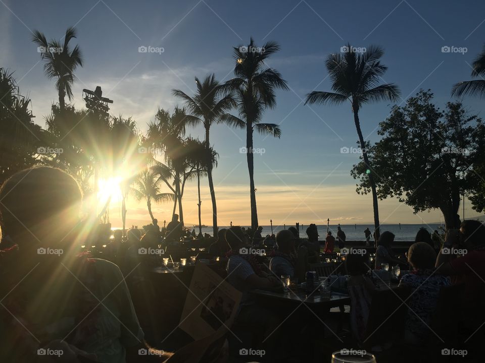 A sunset at a Luau in Hawaii with tall palm trees.