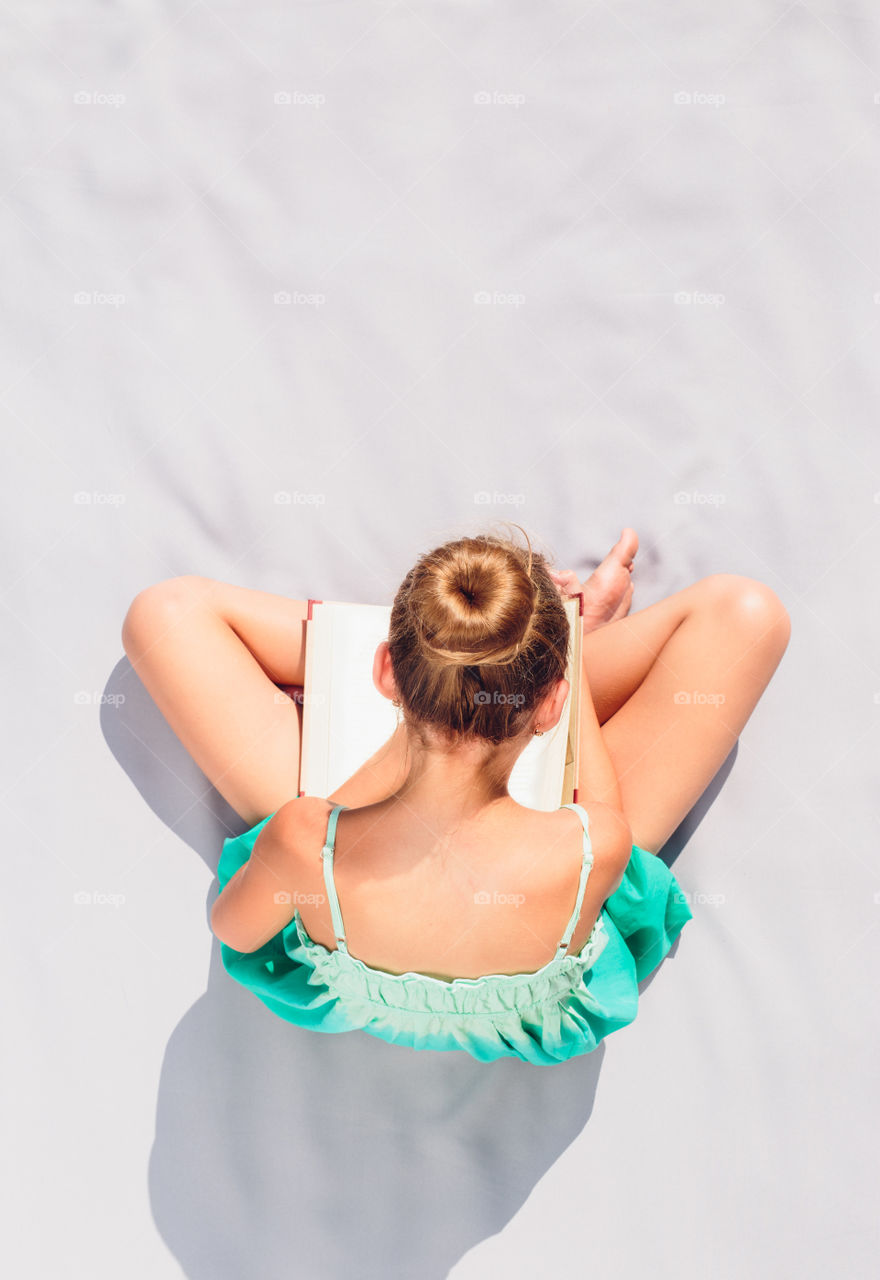 High angle view of girl sitting on bed