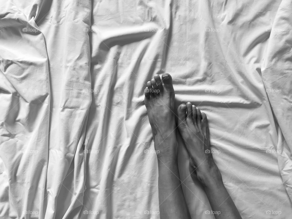 Female feet in white bed black and white 