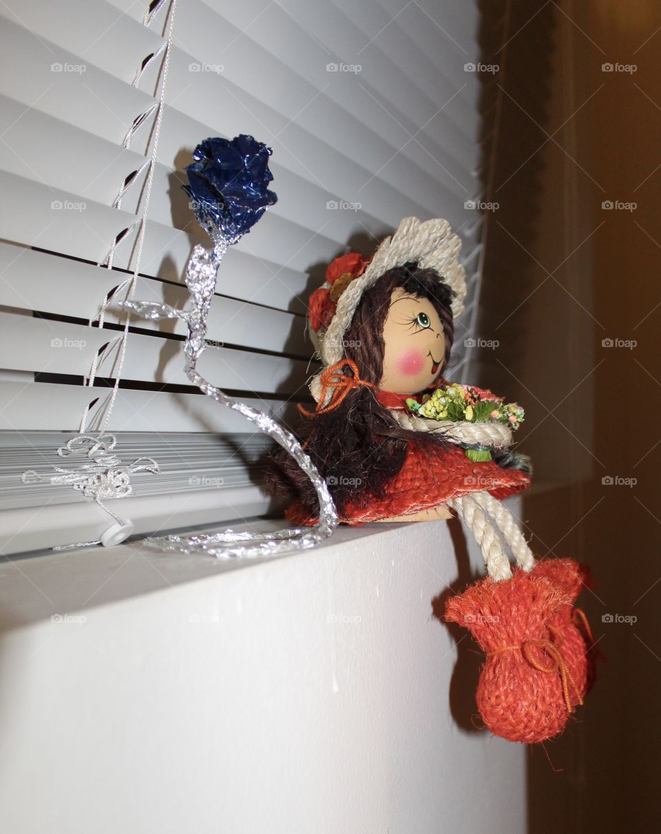 Handcrafted doll next to a silver and blue flower