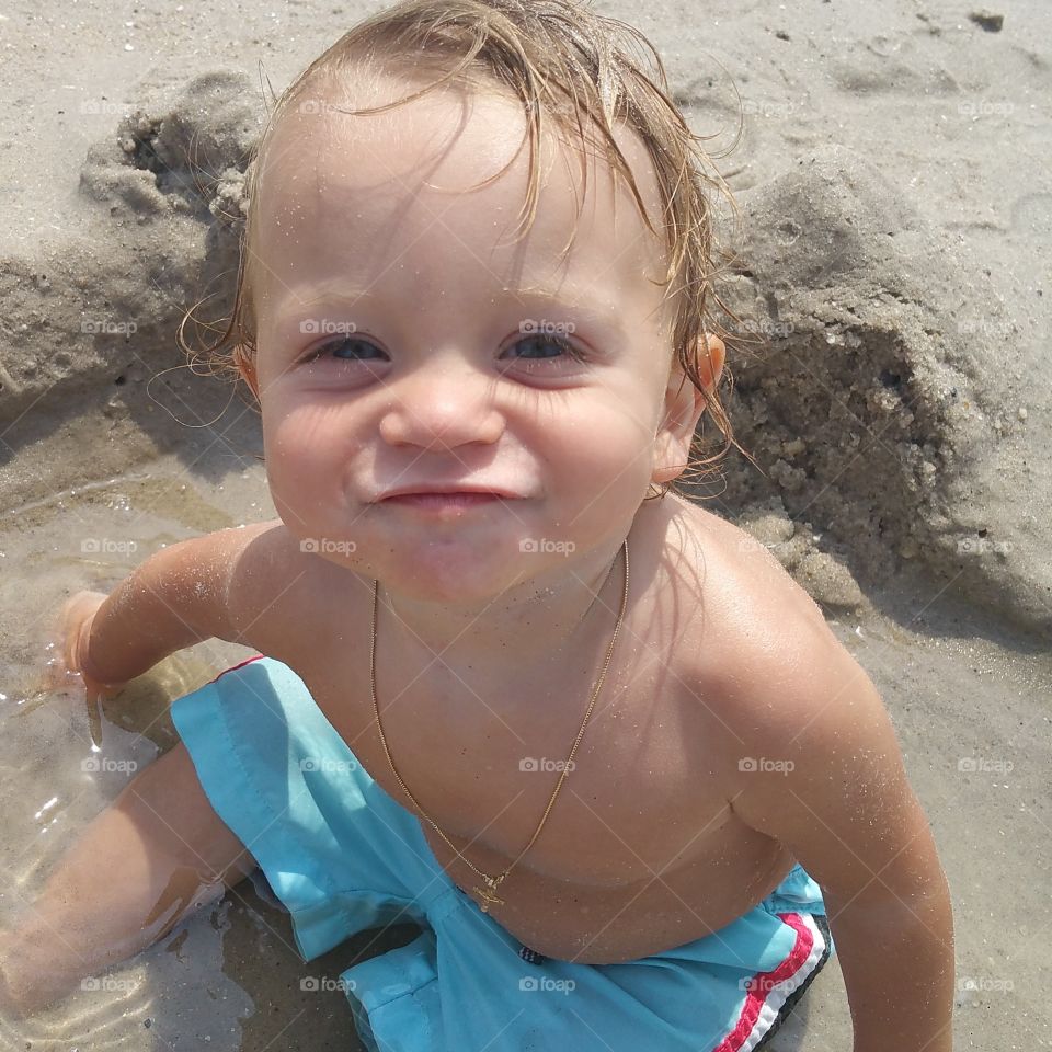 Shirtless baby playing in sand at beach