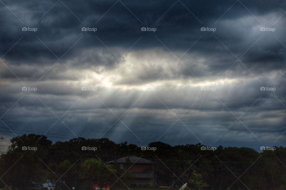 Suns rays streaming through storm clouds over an urban scene 