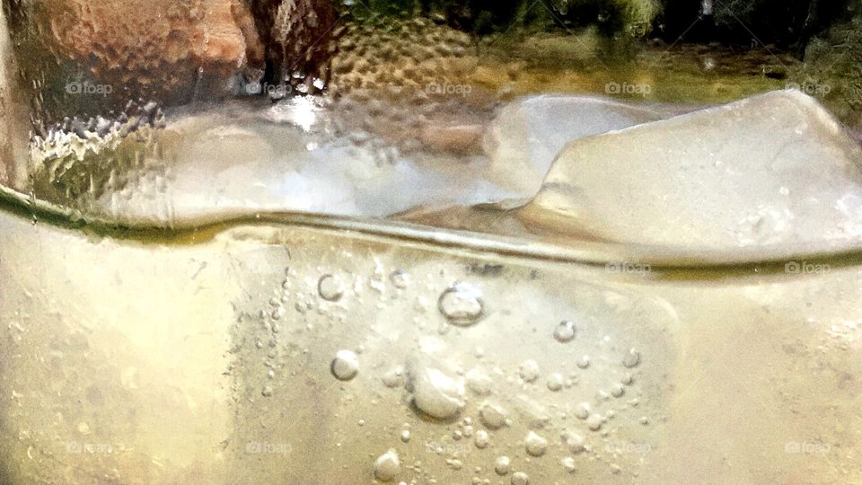 Close up of ice cubes floating in a glass of lemonade. 