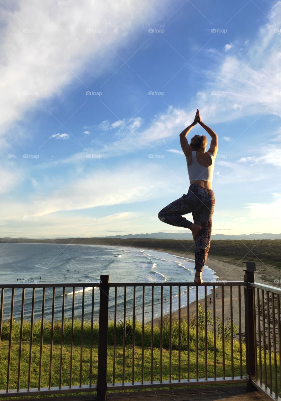 Sunset yoga balancing on a railing at a lookout overlooking a gorgeous Australian beach.