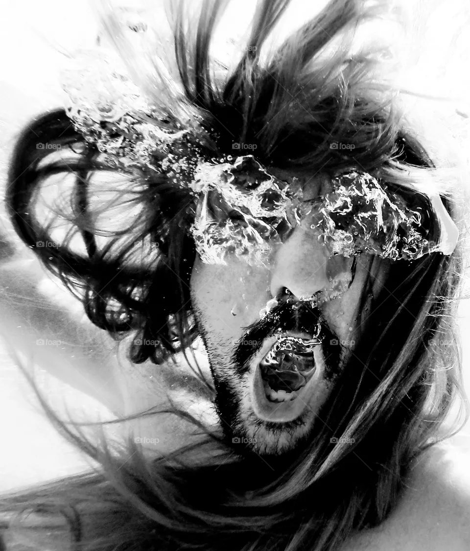 Underwater rock'n'roll with long hair man singing and screaming with water bubbles in his eyes and mouth