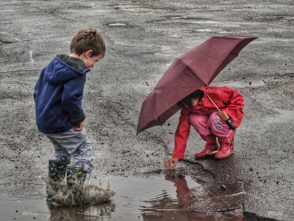 Kids Playing Under An Umbrella. Boy And Girl With Umbrella In The Rain