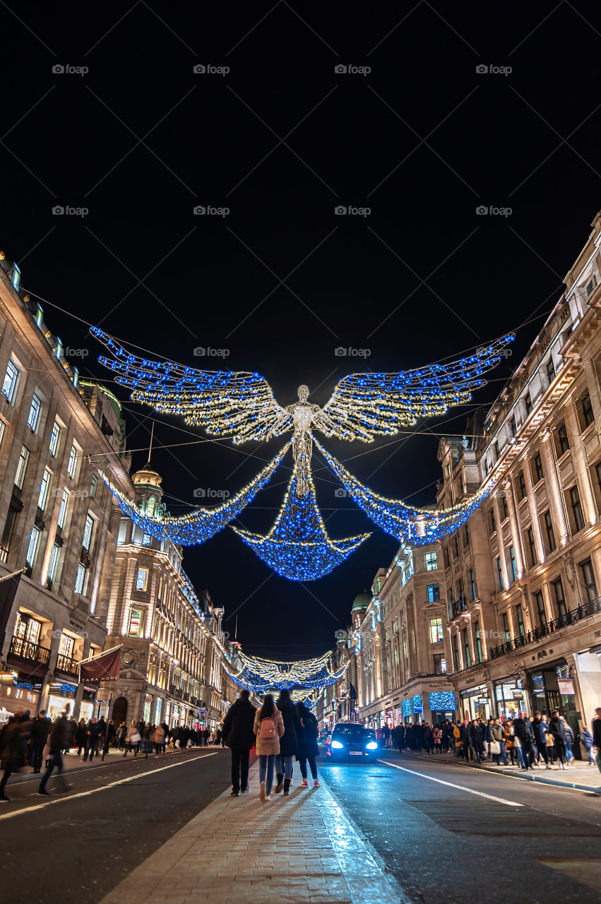 Admiring Christmas Angel decorations in Regent Street and Oxford Street in landmark shopping are in London. UK.