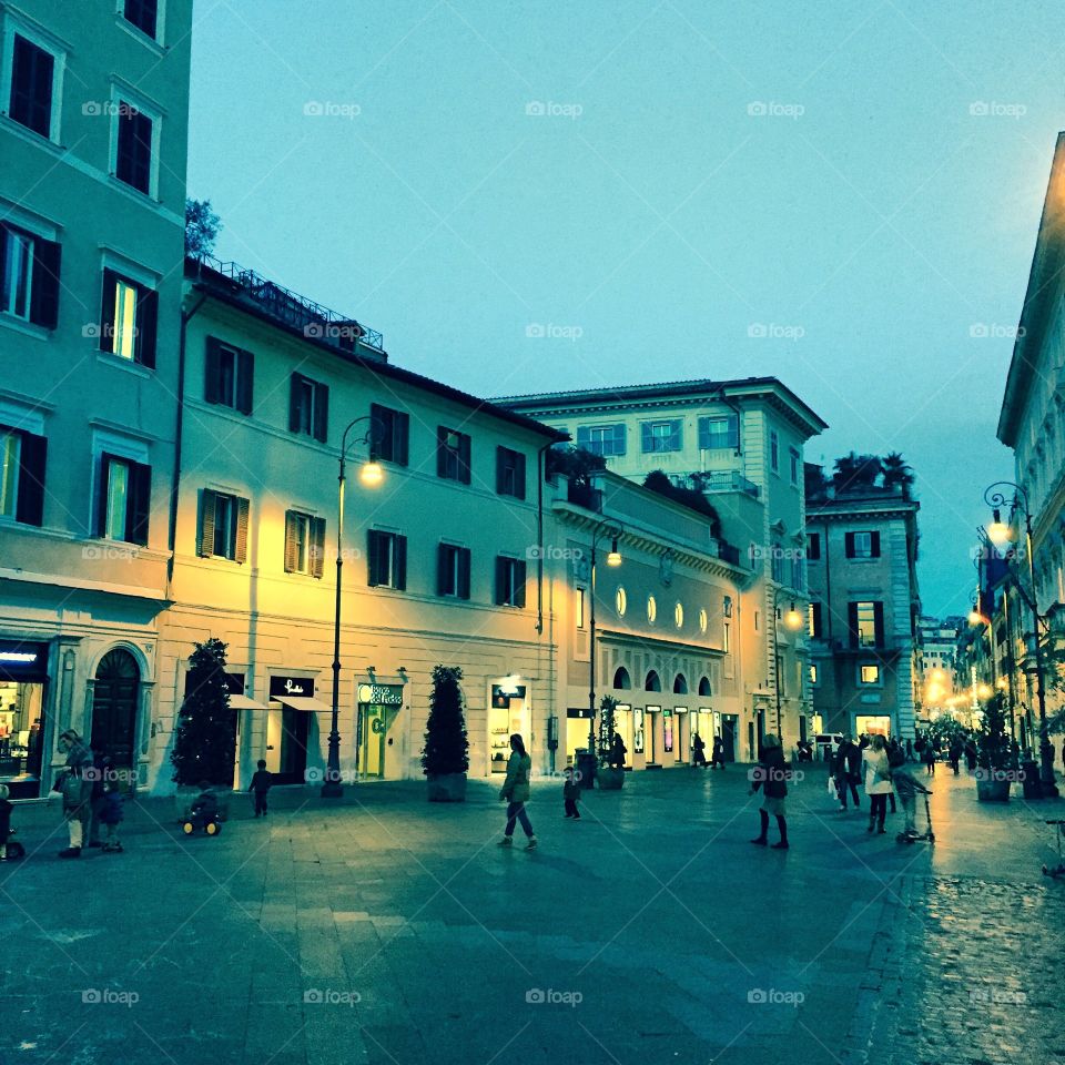 Crowds begin to thin as the night rolls in on a charming cobblestone street in Rome, Italy.