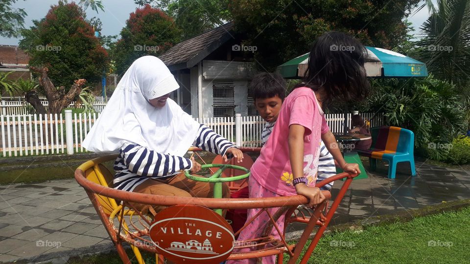 kids try out the merry-go-round in the city park play area in purbalingga, indonesia