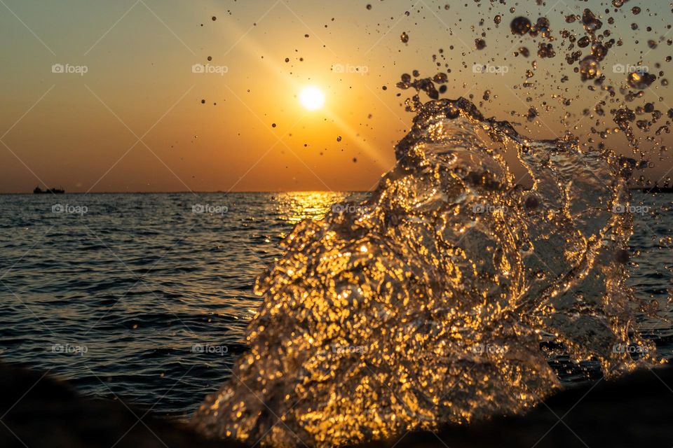 Sea wave splashing in front of the sunset