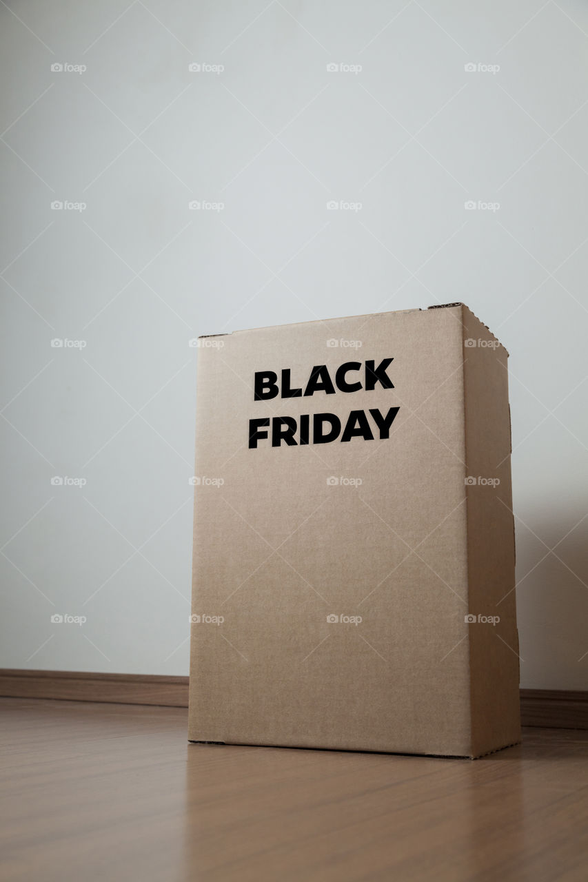 Cardboard box with black friday order written on the box placed on the floor in an empty room with a neutral background. delivery concept. economy concept. black friday concept. shopping concept.
