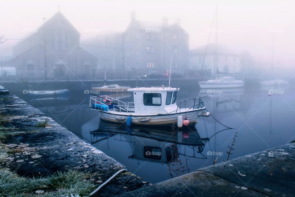 white wooden boat on cold foggy morning at Claddagh in Galway city, Ireland