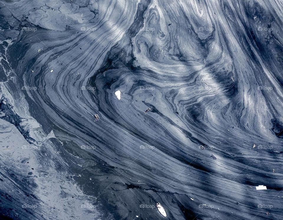  abstract pattern formed by oil slick and urban runoff pollution