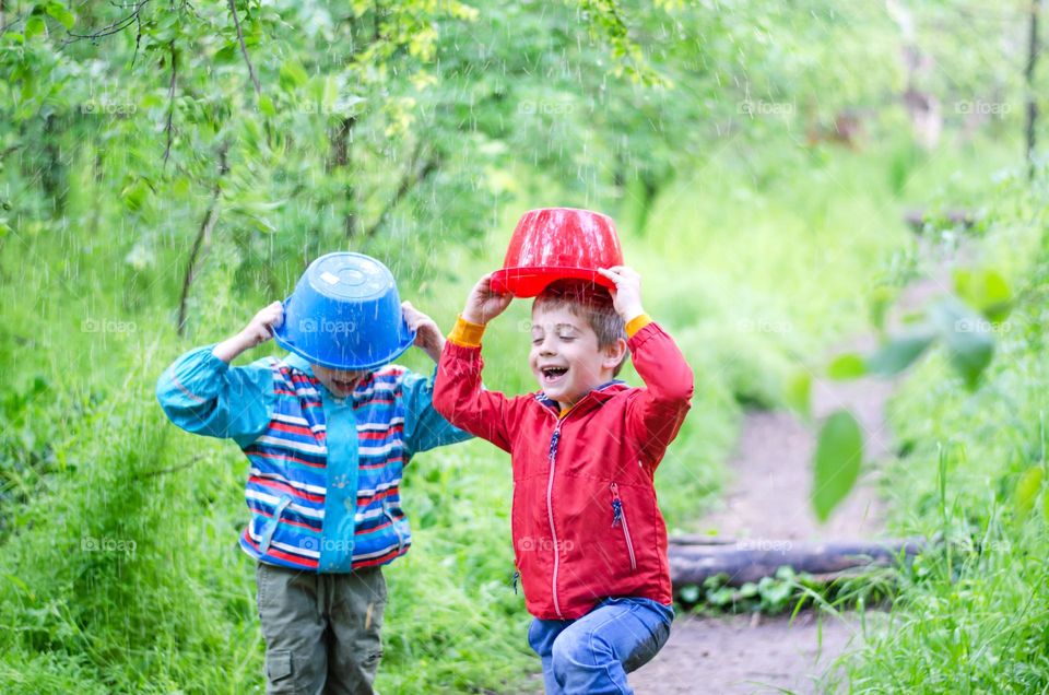 Children Playing in Rainy Spring Day with Buckets on Their Heads