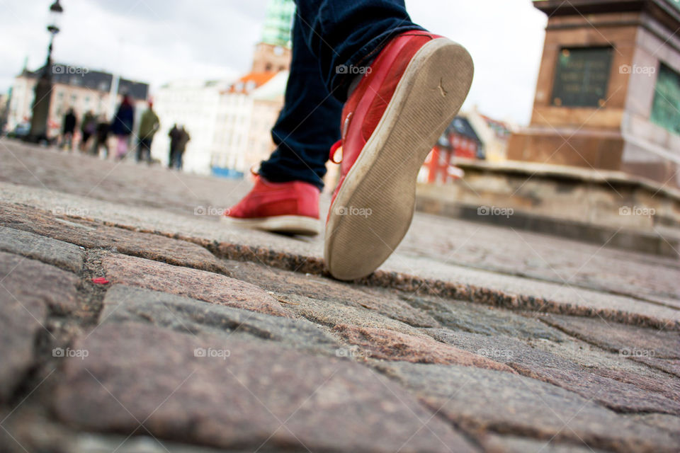 Lower section view of a person walking on sidewalk