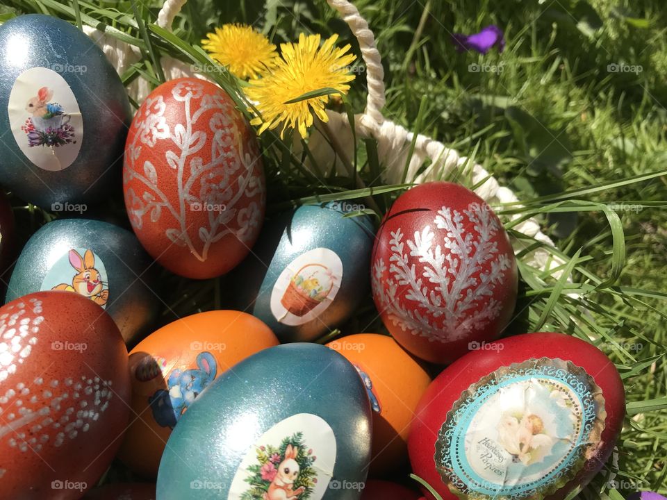 Easter eggs in a basket in the grass on Easter day, there are different colors of them.