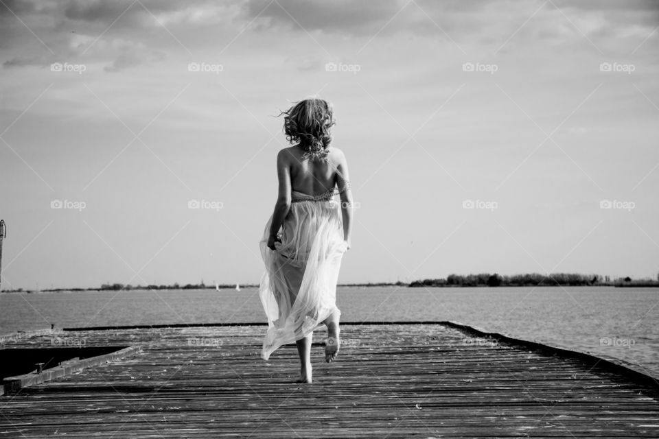 woman dancing on deck at lake. woman in beautiful dress dancing on the deck at lake