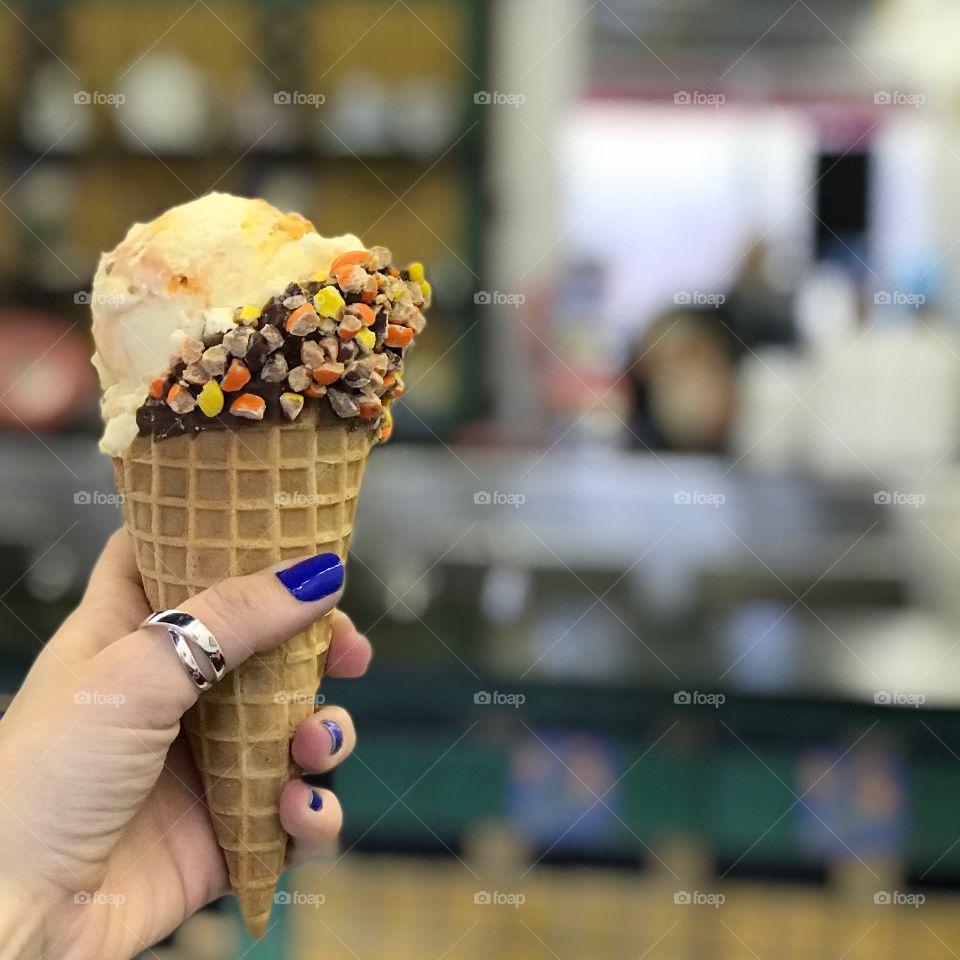 Holding an ice cream cone with reese’s pieces on waffle cone 