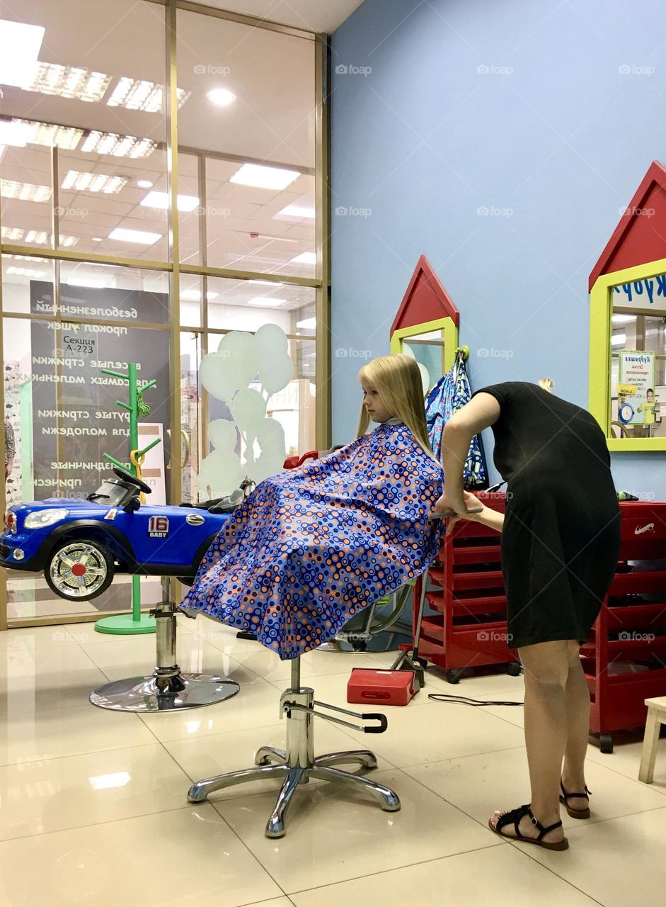 Little girl cutting hair in beauty salon