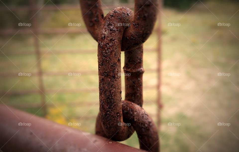 Old rusty piece of chain on a gate an ellipses