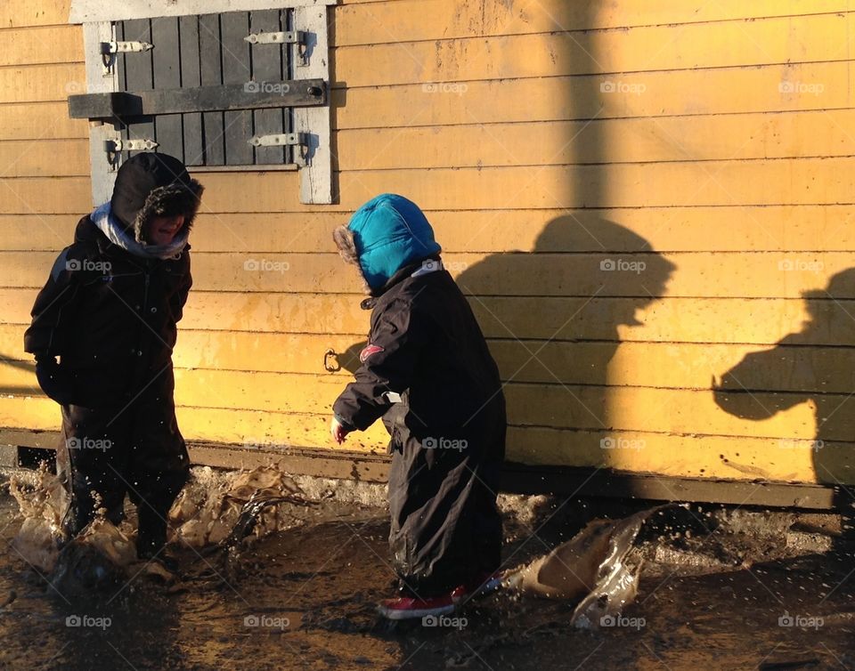 Kids playing in a puddle in front of yellow playhouse

