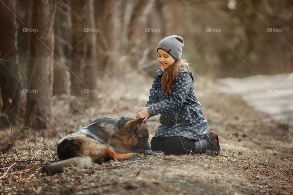 Girl walking with German shepherd puppy in a spring forest 