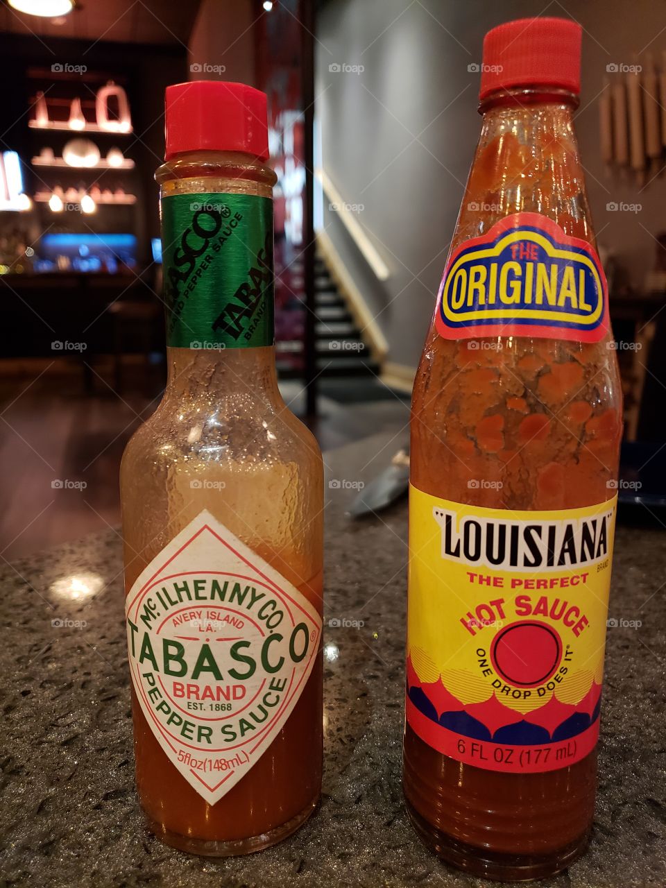 Two red hot sauce bottles on a restaurant table in Biloxi.