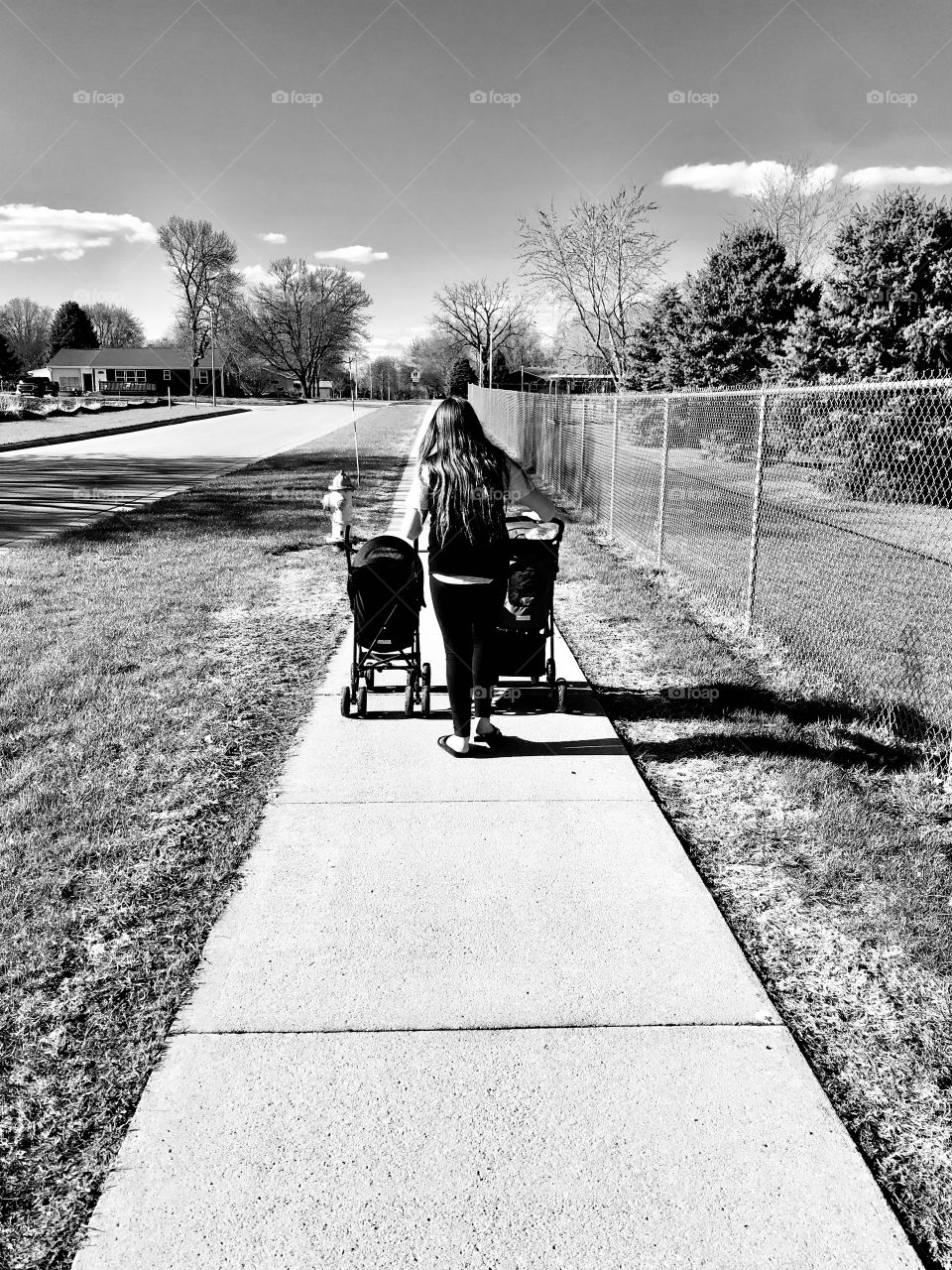 Darling black and white photo of young girl pushing her kitties in strollers for an afternoon ride. 