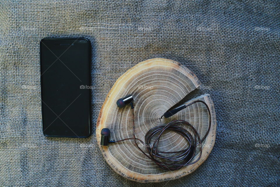 vacuum headphones and smartphone on the cut of a cut tree